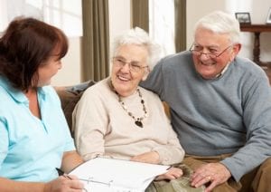 A senior couple sitting close to one another speak with a Culpepper employee as they all sit on a couch with some papers.