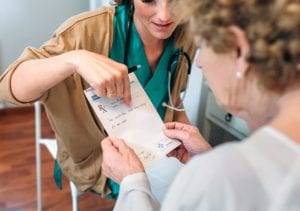 A new prescription medication is explained to a resident as it's handed to her.