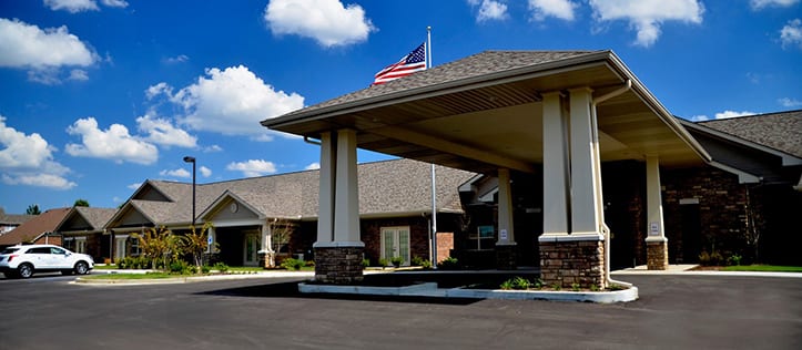 An outdoor view of the Culpepper Place assisted living facility in Olive Branch, MS that reveals an American flag and cloudly blue skies.