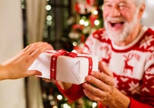 An excited male resident receives a christmas gift in a box with a bow.