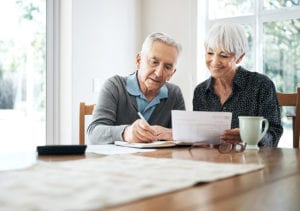 A senior couple sit close to one another as they discuss finances