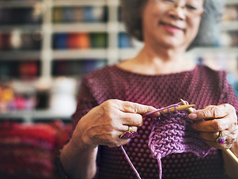A senior resident looks happy and content as she knits while sitting in a room meant for pursuing hobbies.