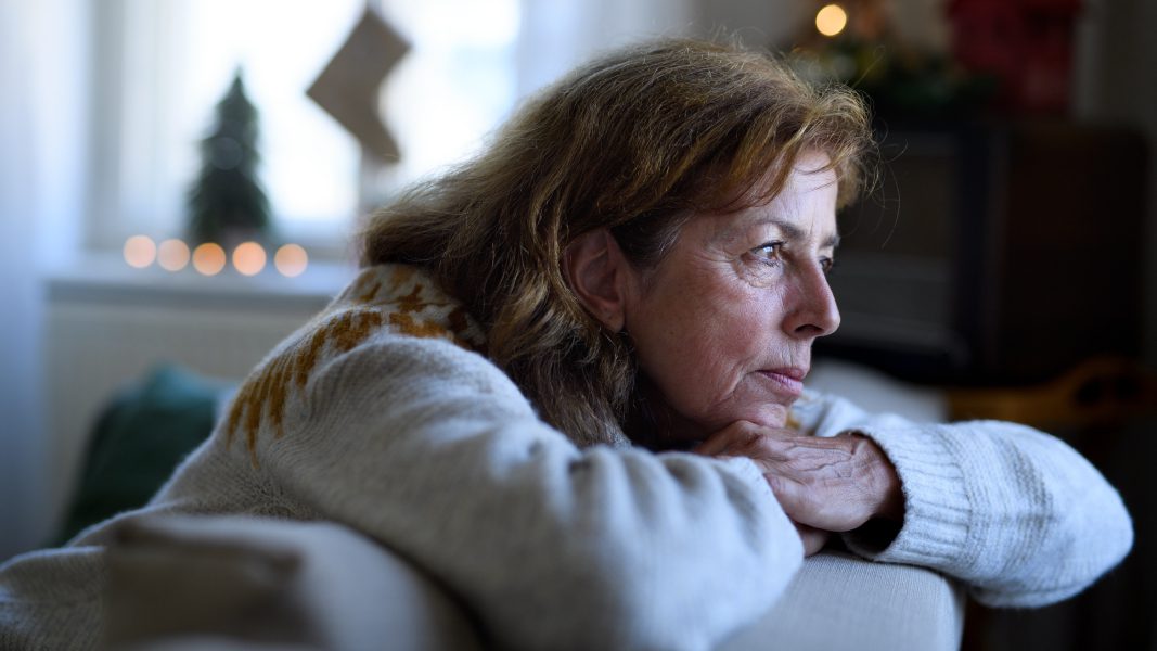 A woman suffering loneliness stares out the window.